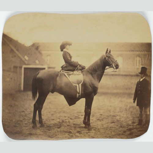 Old (sepia) photo of a woman on a horse, wearing equestrian clothing.