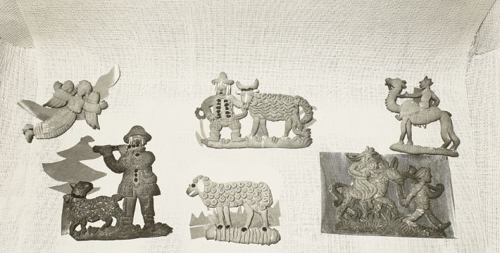 Six folk art cookie molds featuring animals, people, and angels displayed on a textured white background.