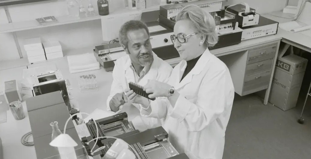 A black and white photo of two people in lab coats