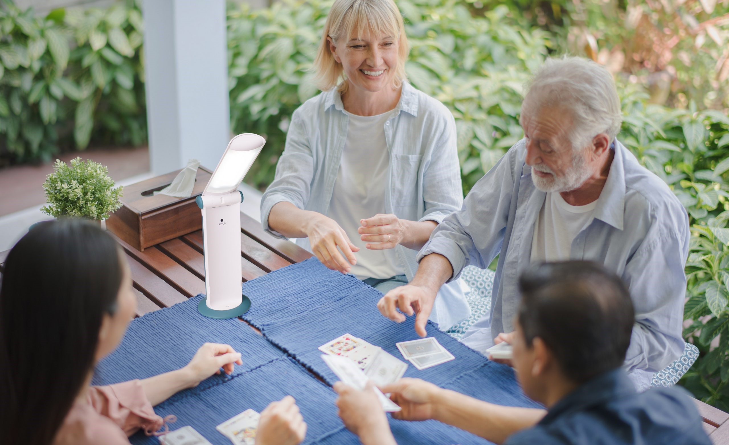 4 mensen die een Daylight-lamp gebruiken om te kaartspellen