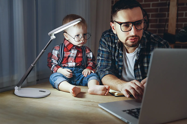 Man die een daglichtlamp gebruikt om samen met zijn kind op de computer te kijken