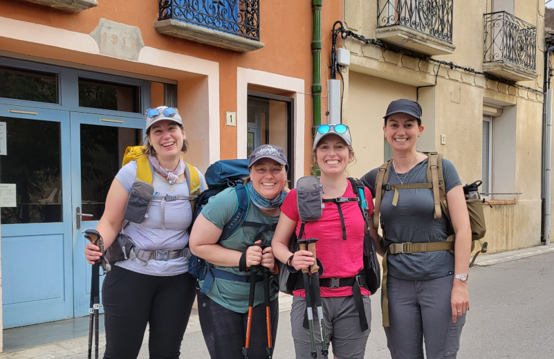 Four women hikers standing in a french town as they complete a section hike of the Sentier de Cathar.