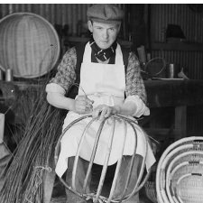 A black and white photo of a man weaving baskets