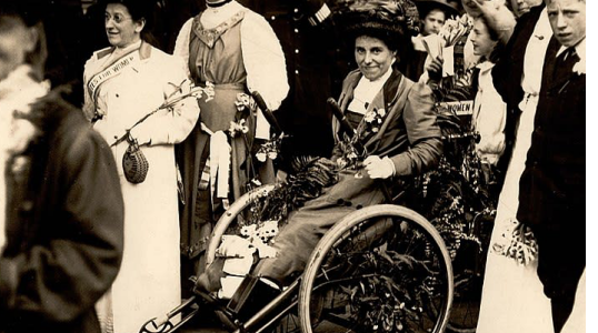 Rosa May Billinghurst  in a wheelchair surrounded by a group of women