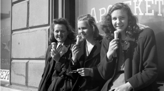 A black and white photo depicting three girls eating ice cream