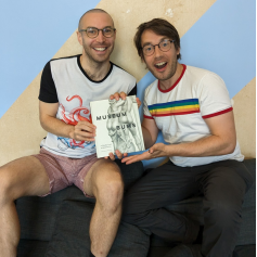 A photo of two happy men holding a book