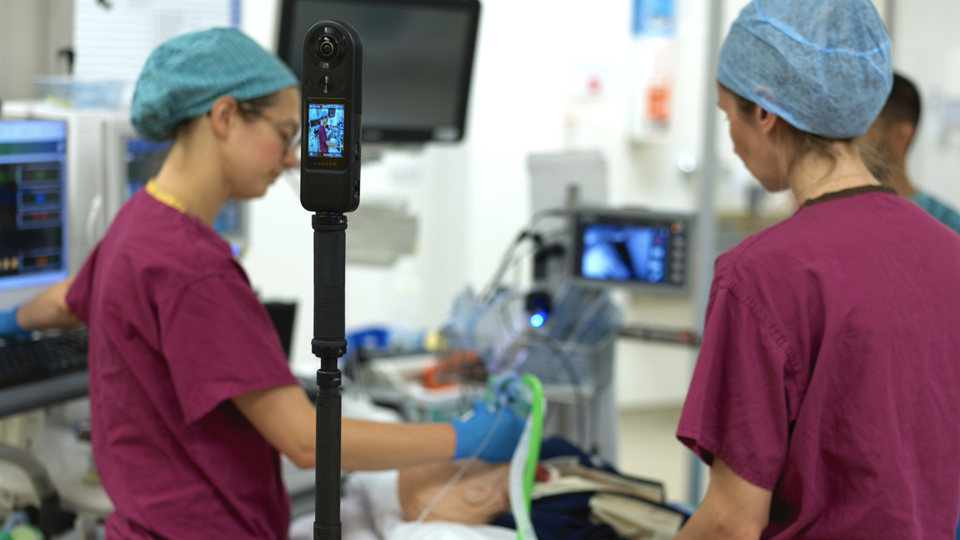 Medical staff working in an operating theatre being filmed while they work.